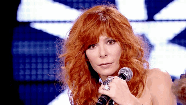 a woman with red hair holds a microphone in her hand