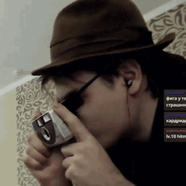 a man wearing a hat and sunglasses is taking a picture with a camera