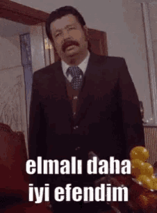 a man in a suit and tie is standing in front of a bowl of lemons and says elmali daha iyi efendim