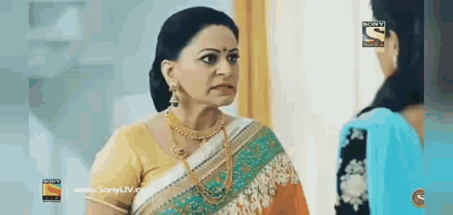 a woman in a saree is standing next to another woman in a blue dress .