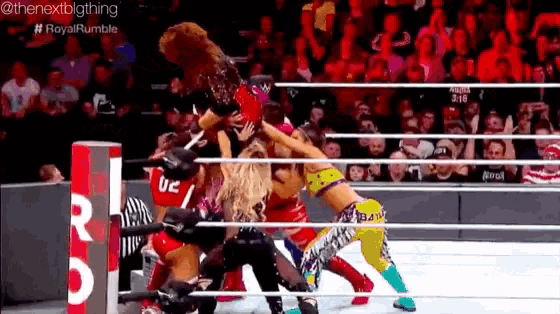 a group of women are wrestling in a ring with a referee wearing a uc shirt