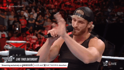 a man in a black tank top is holding a microphone in front of a crowd and says summerslam live this saturday