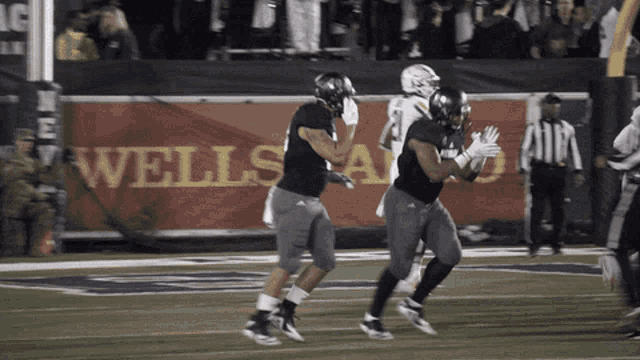 a wells fargo sign is behind two football players