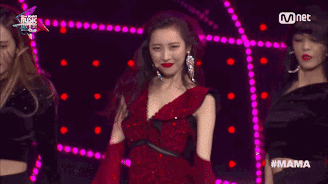 a woman in a red dress is performing on a stage with mnet written on the bottom