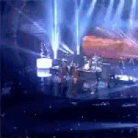 a group of people are playing drums on a stage in a dark room .