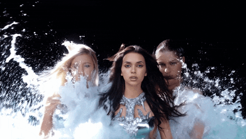 a woman in a silver dress is surrounded by two other women in the water