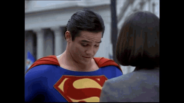 a man in a superman costume stands next to a woman