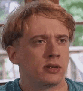 a close up of a man 's face with a blue shirt on .