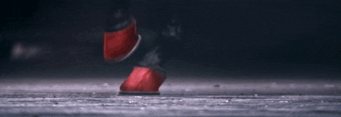 a close up of a person 's feet in red shoes walking on a wet floor .
