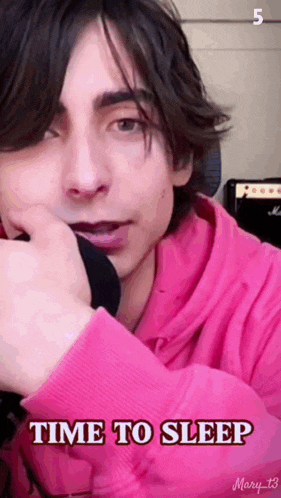 a young man wearing a pink hoodie with the words time to sleep written on it