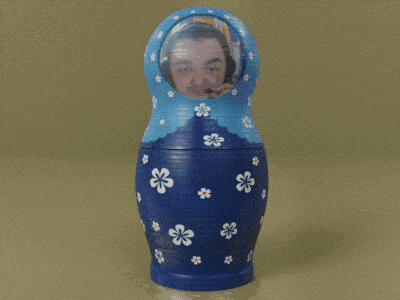 a blue green and orange matryoshka doll with a reflection of a person 's face