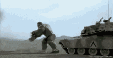 the hulk is standing next to a tank in a desert .