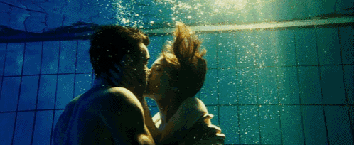 a man and woman are kissing underwater in a swimming pool