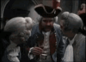 a man in a pirate hat is talking to two other men .