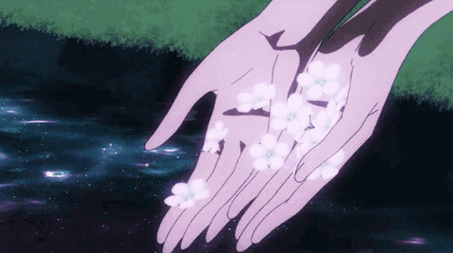a person holding flowers in their hands in front of water