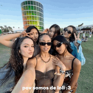 a group of young women are posing for a selfie in front of a rainbow colored building .