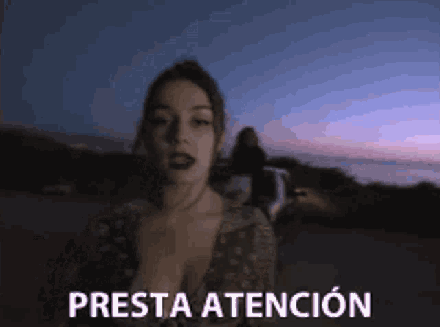 a woman is standing in front of a sign that says presta tencion