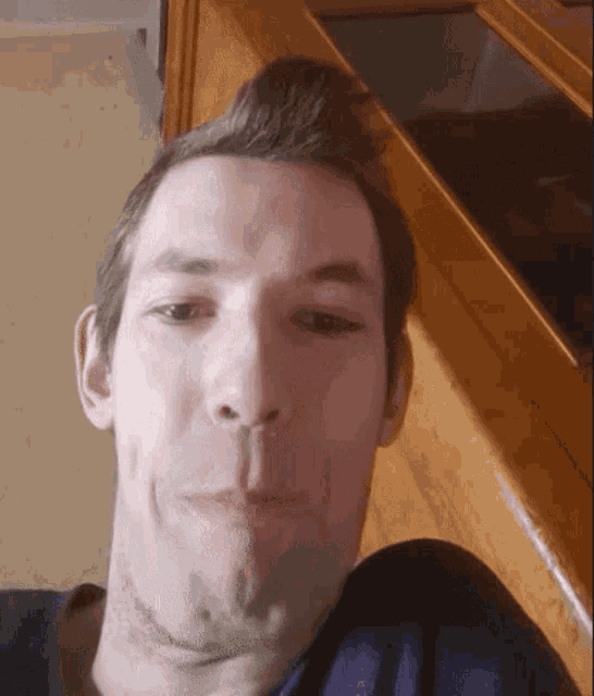 a close up of a man 's face with a wooden counter in the background