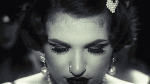 a close up of a woman 's face with a nose ring and earrings