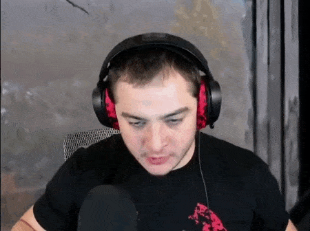 a man wearing headphones is making a funny face while sitting in front of a microphone .