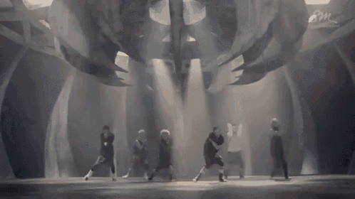 a group of men are dancing on a stage in a dark room .