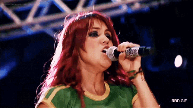 a woman with red hair singing into a microphone with rbd.gif written below her