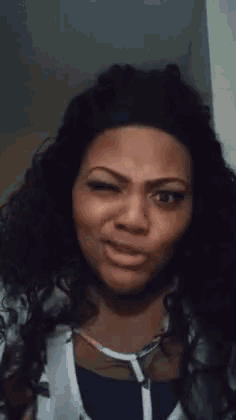 a woman with curly hair is making a funny face while looking at the camera .