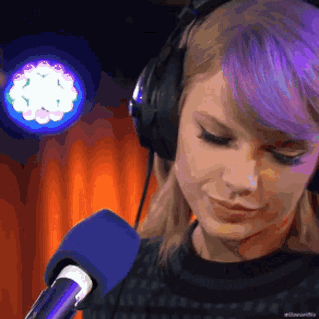 a woman with purple hair is wearing headphones and looking at a microphone