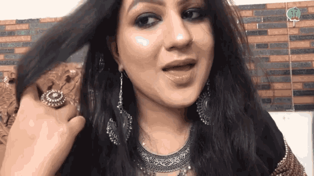 a woman is wearing a necklace and earrings and has a ring on her finger