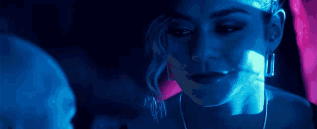 a close up of a woman 's face in a dark room with blue lights shining on her face .