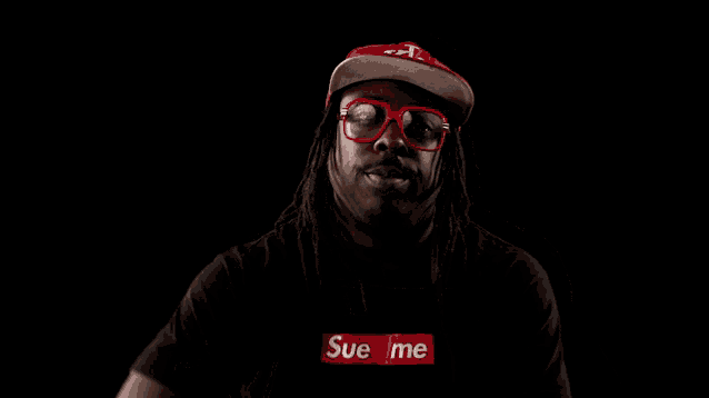 a man wearing a black shirt that says sue me is pointing