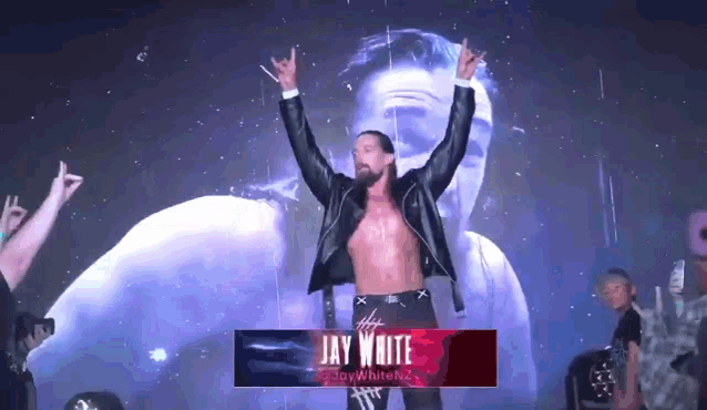 a wrestler named jay white is standing on a stage with his hands in the air