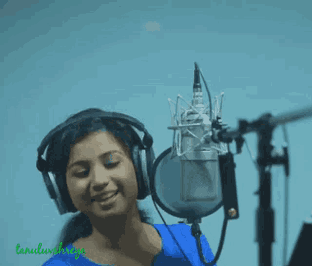 a woman wearing headphones is singing into a microphone with the name lanulivsreya written on the bottom