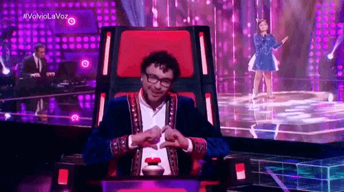 a man is sitting in a chair on a stage in front of a girl singing .
