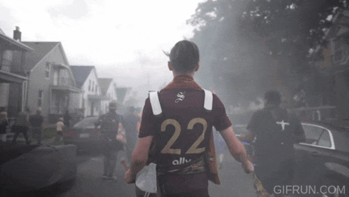a man wearing a jersey with the number 22 walking down a street