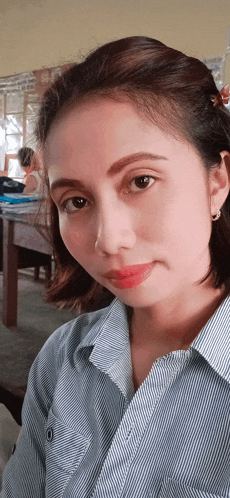 a woman in a blue and white striped shirt is taking a picture of herself