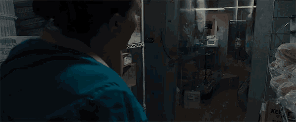 a woman in a blue shirt is standing in a dark room with a box that says kellogg on it