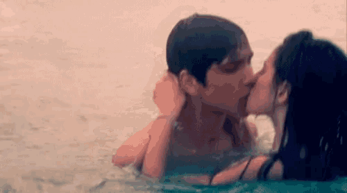a man and a woman kissing in the water .