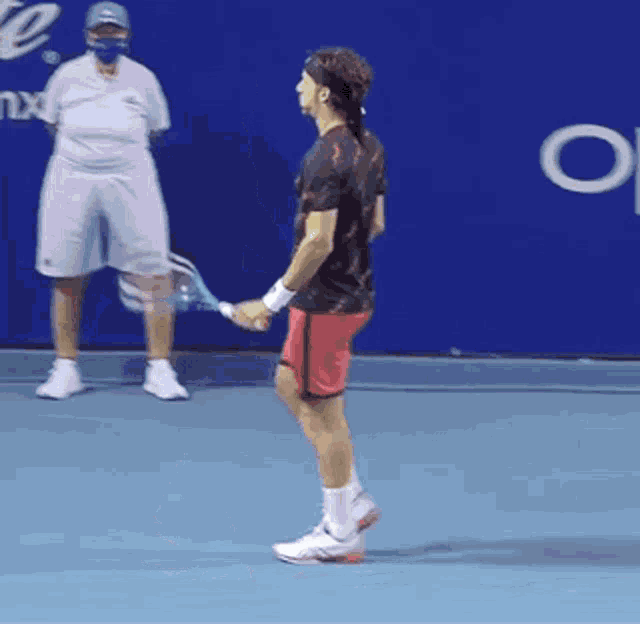 a man is holding a tennis racquet on a blue court