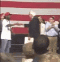 a man in a suit is shaking hands with a woman in a red hat .