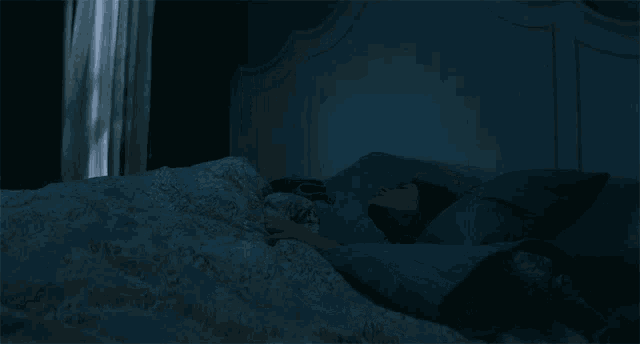a woman is laying in bed with a blue comforter
