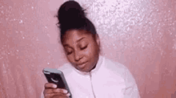 a woman is looking at her cell phone and making a funny face .