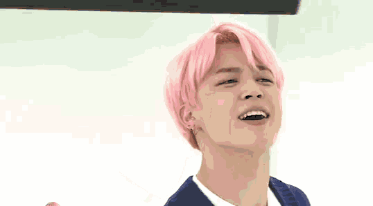 a young man with pink hair is making a funny face and looking at the camera .