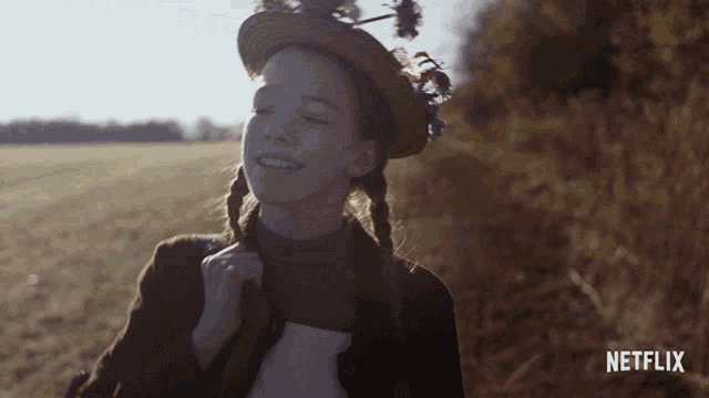 a girl wearing a straw hat with flowers on it is smiling in front of a netflix logo