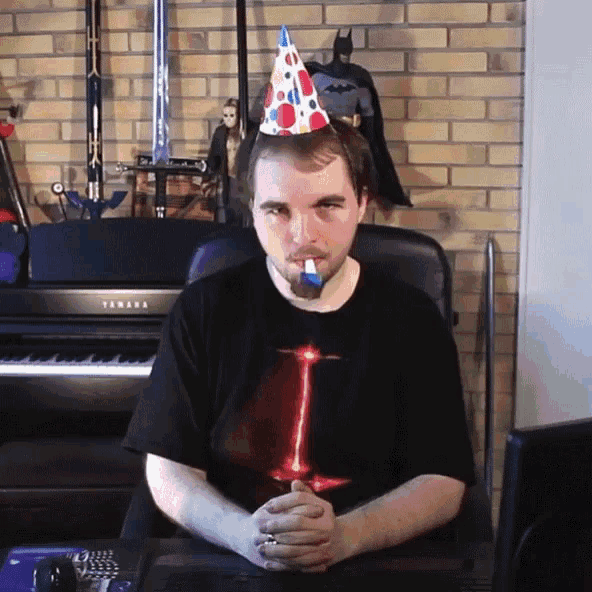 a man wearing a birthday hat is sitting in front of a yamaha keyboard