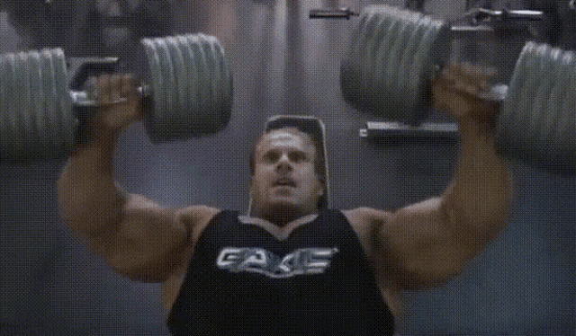 a man is lifting dumbbells in a gym wearing a black tank top that says fake