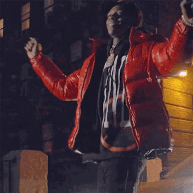 a man in a red jacket is making a peace sign with his hands