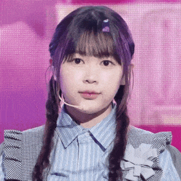 a girl with braids and a microphone on her head looks at the camera