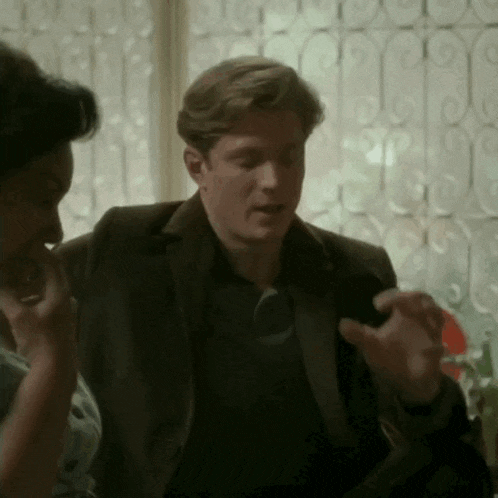 a man in a suit and tie is talking to a woman in a black shirt .
