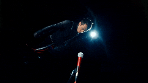 a man in a black suit is holding a red microphone